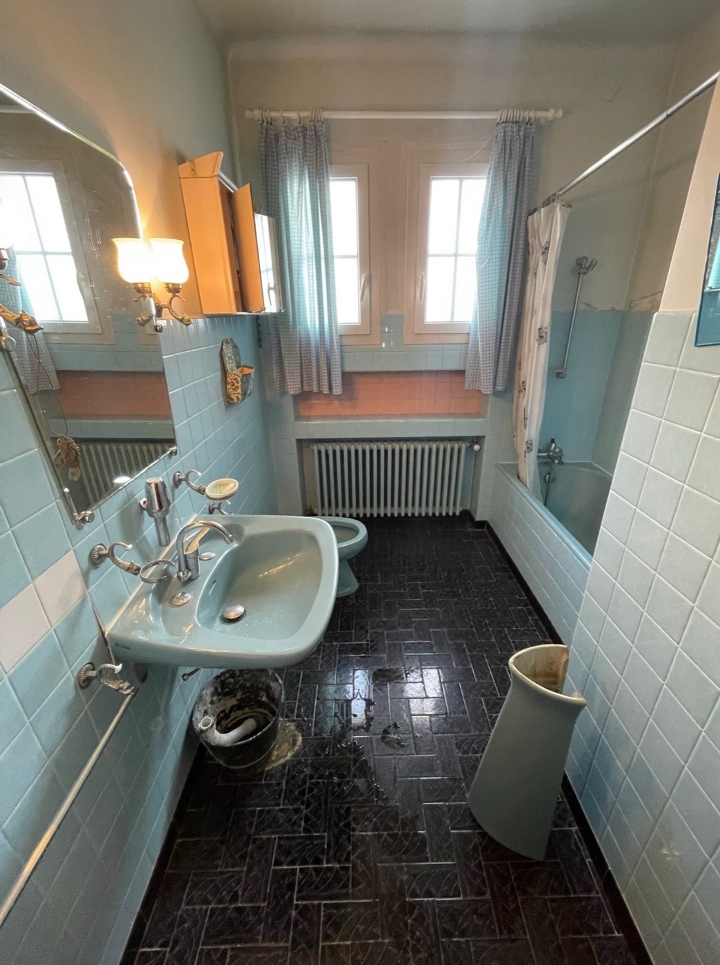 Salle de bain des années 70 avant rénovation à Pertuis : lavabo bleu scellé au mur, faïence bleue et sol ancien