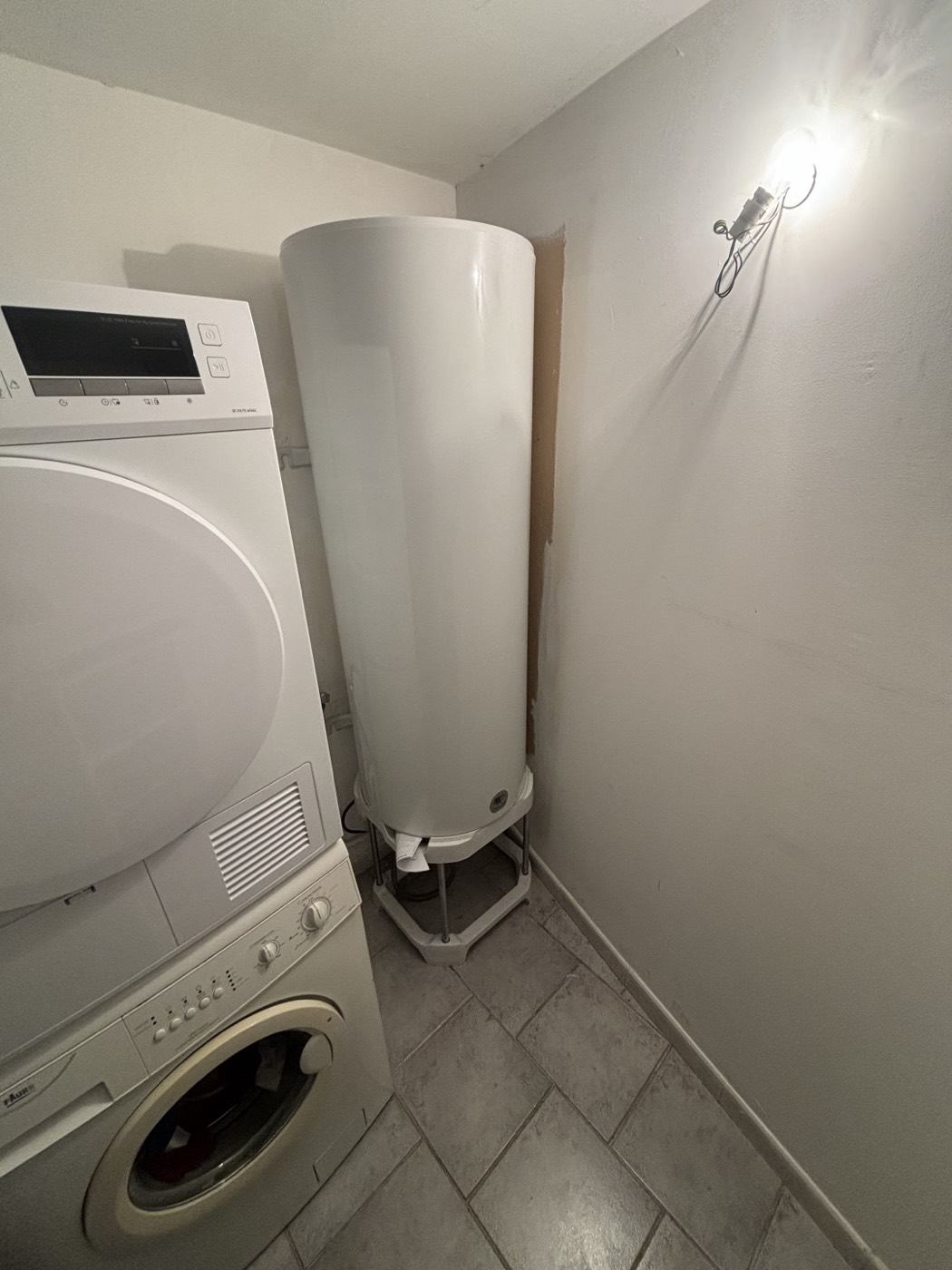 Chauffe-eau électrique neuf installé dans une buanderie, à côté du lave-linge et du sèche-linge